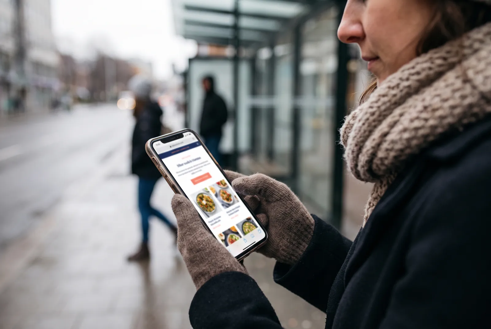 A woman at a bus stop browsing a restaurant menu that loaded instantly on her phone